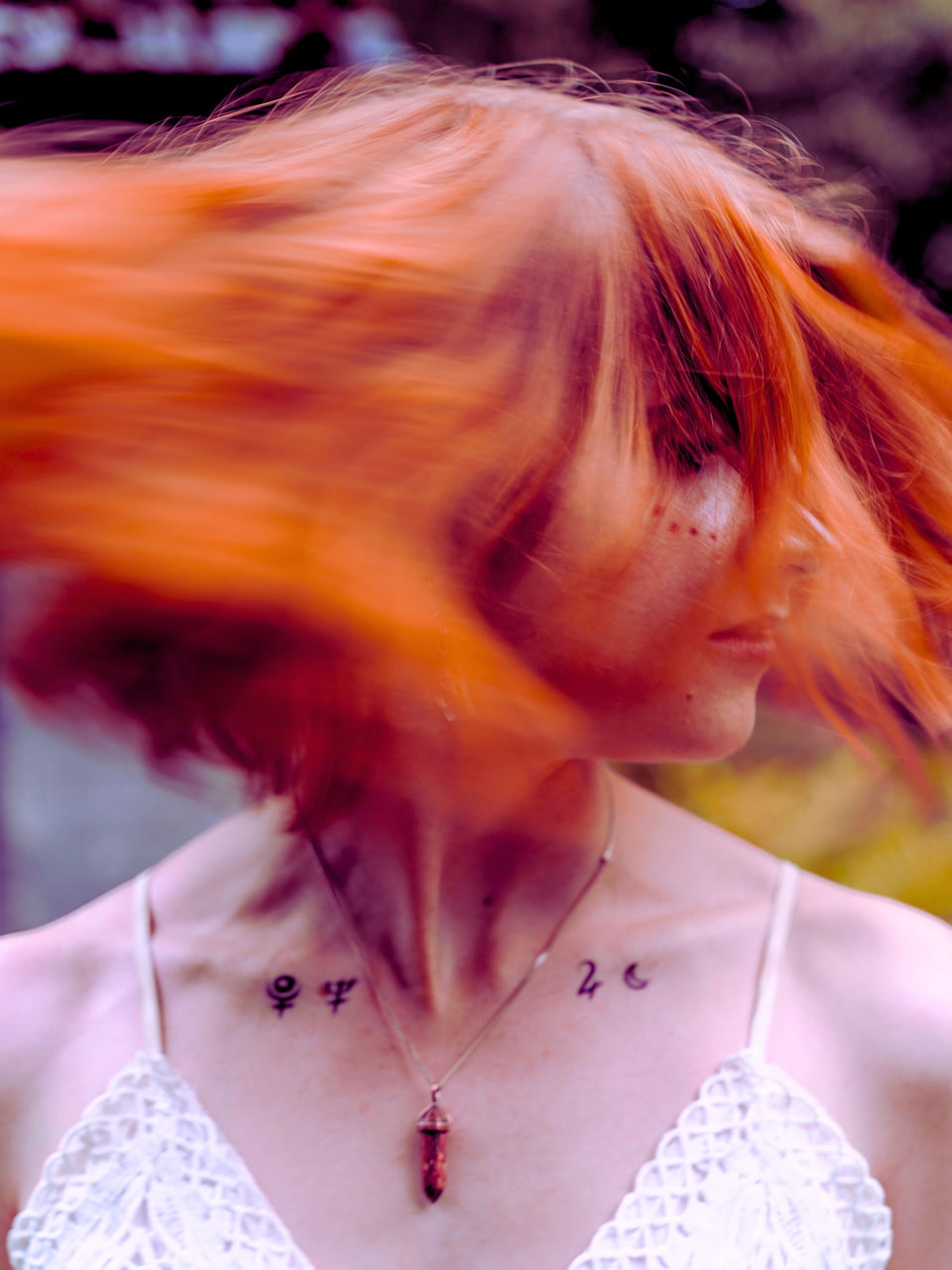 Visual für Sandra Clementes Angebot "Feminine Archetypenreise" zeigt eine mit Runen tätowierte Frau, die ihre roten Haare schüttelt, den Kopf von dem Kamera weggedreht