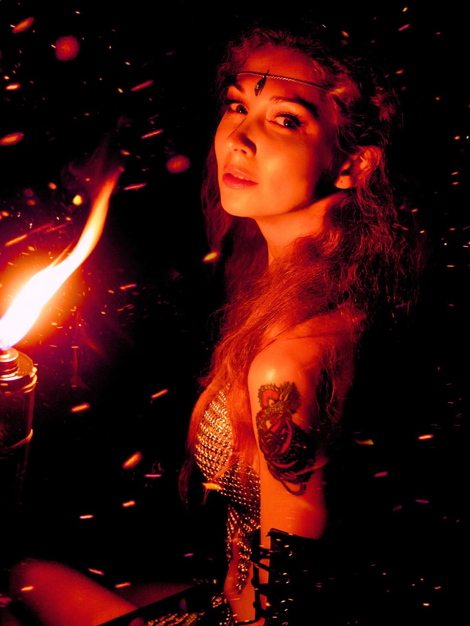 Visual für Sandra Clementes Angebot "Feminine Archetypenreise" zeigt eine Kriegerin mit Fackel und fliegenden Funken bei Nacht