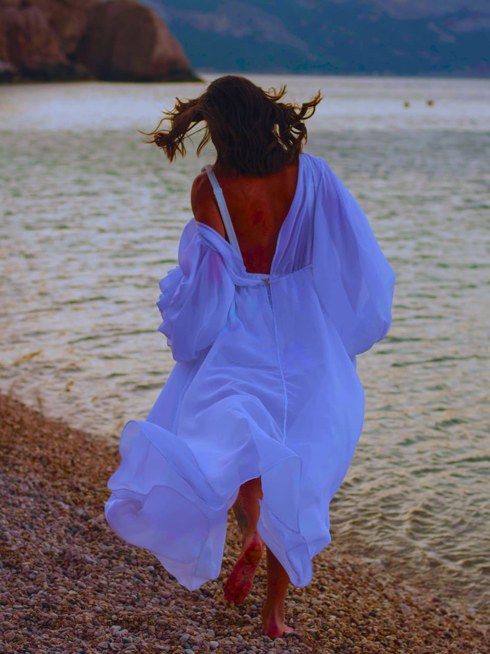 Key Visual für Sandra Clementes Angebot "Soul Journey Premium" zeigt eine Frau im weißen Sommerkleid am Strand laufend
